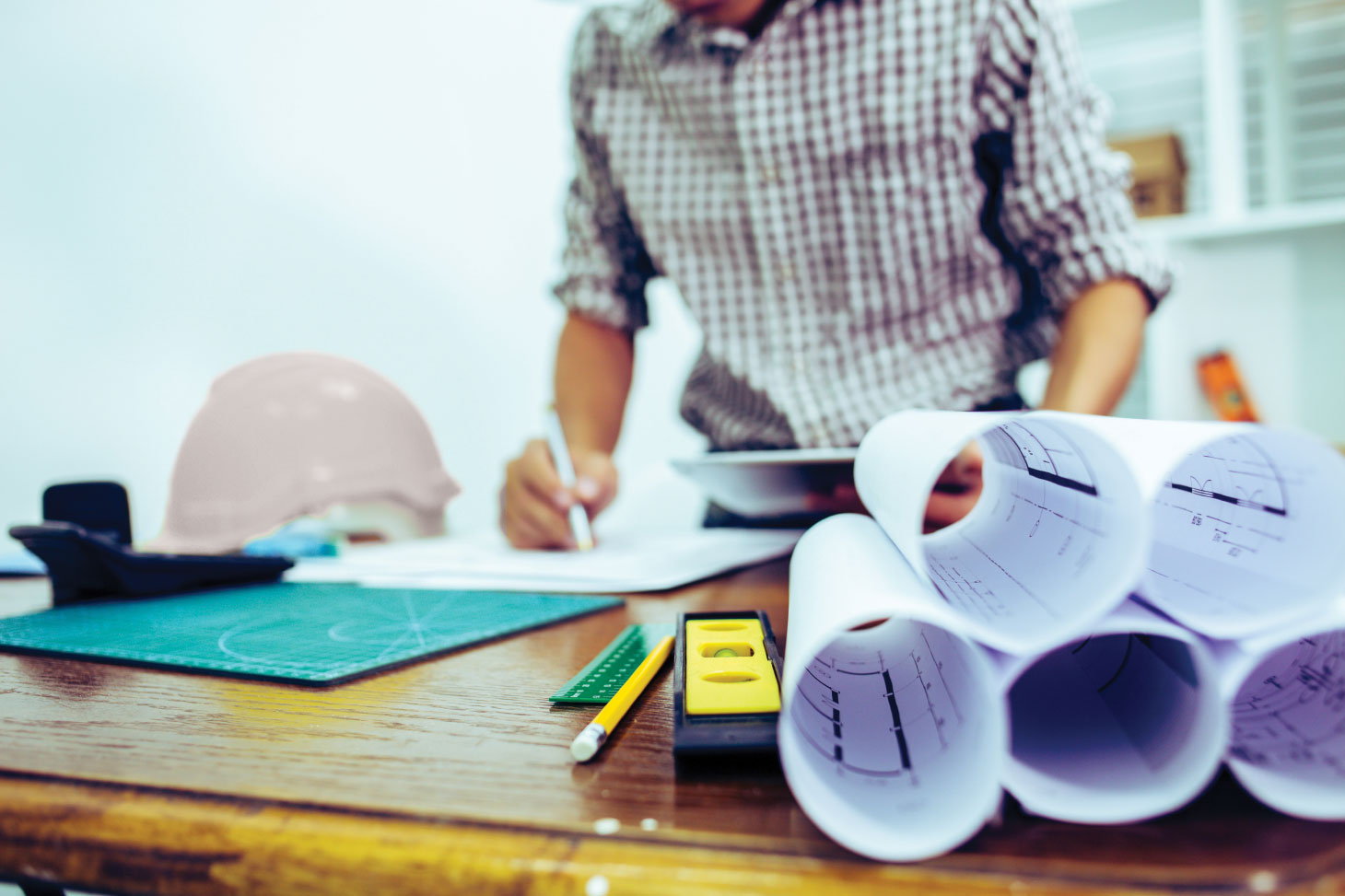 Man at desk with rolls of designs and plans