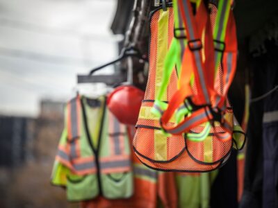 Safety vests and helmets hanging on hooks and hangers