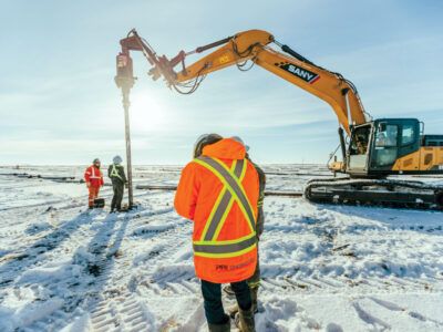 Worker on site, drilling in snow-covered ground