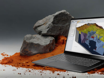 Laptop sitting on soil with larger rock in background