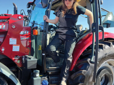 Woman in Dirty Seahorse Zenith coveralls on red tractor
