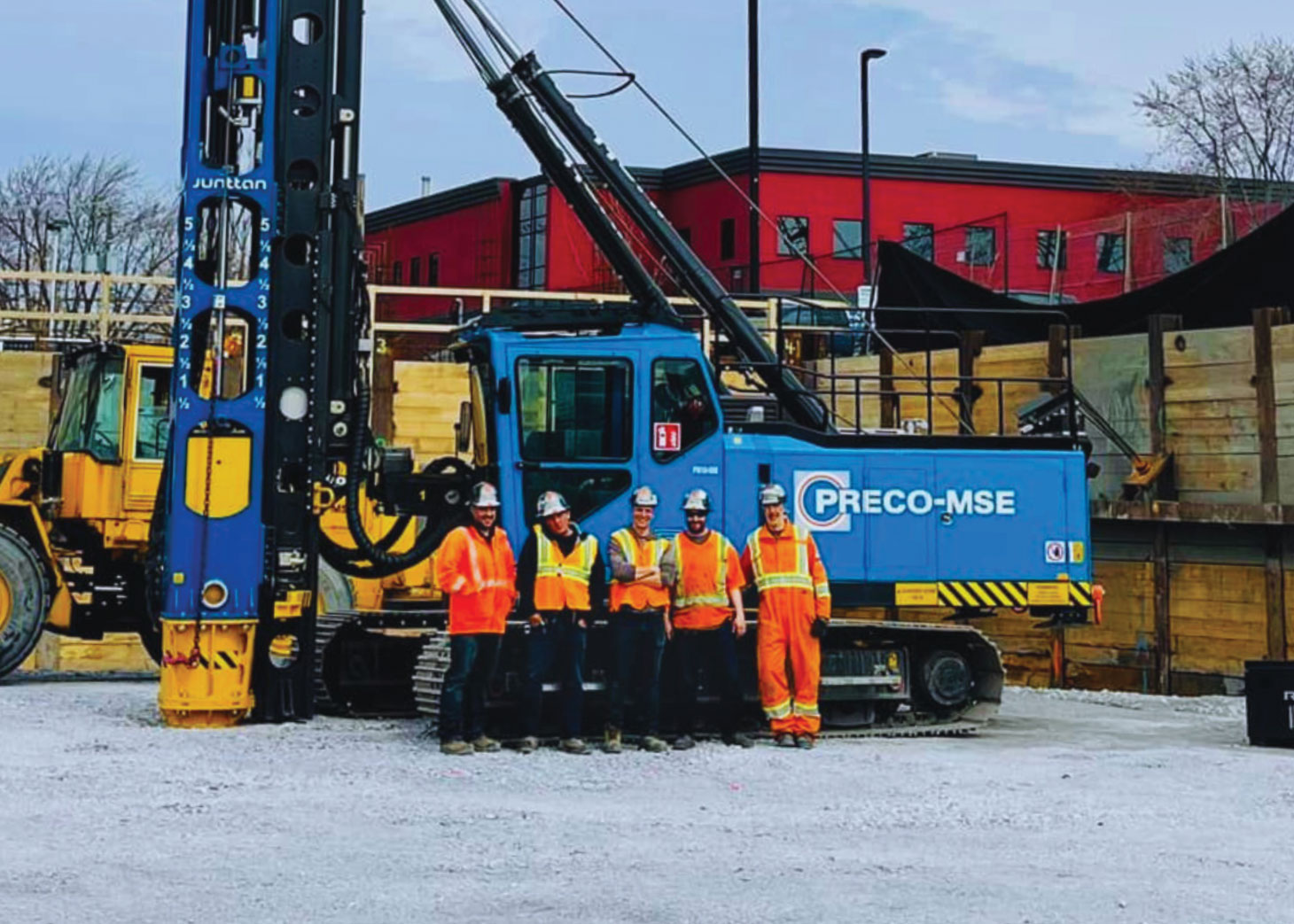 Group photo in front of blue, PRECO-MSE branded drilling rig // Photo de groupe devant une foreuse bleue de marque PRECO-MSE