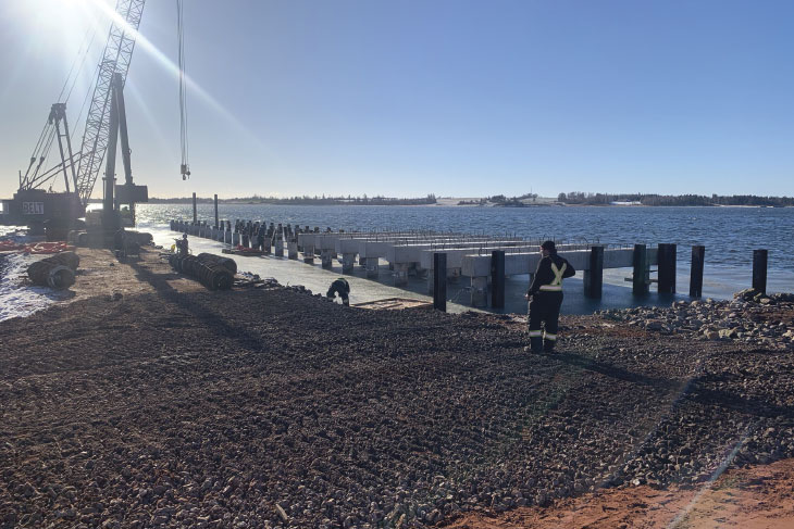 Crane on pier construction site, with bright sunshine in background