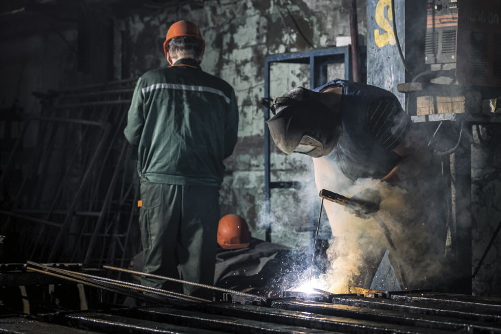 Industrial worker at a factory welding steel structure