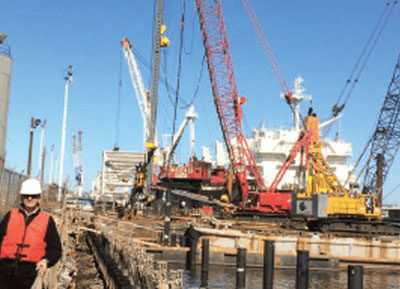 Louis Frits standing on dock, with cranes in background