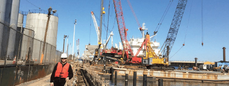 Louis Frits standing on dock, with cranes in background