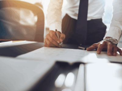 Closeup of man writing on papers at his desk