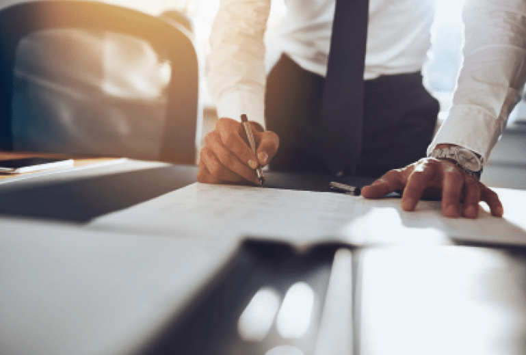 Closeup of man writing on papers at his desk