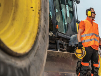 Construction worker standing beside tractor