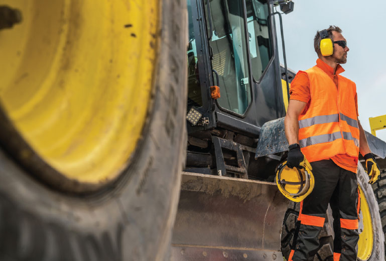 Construction worker standing beside tractor