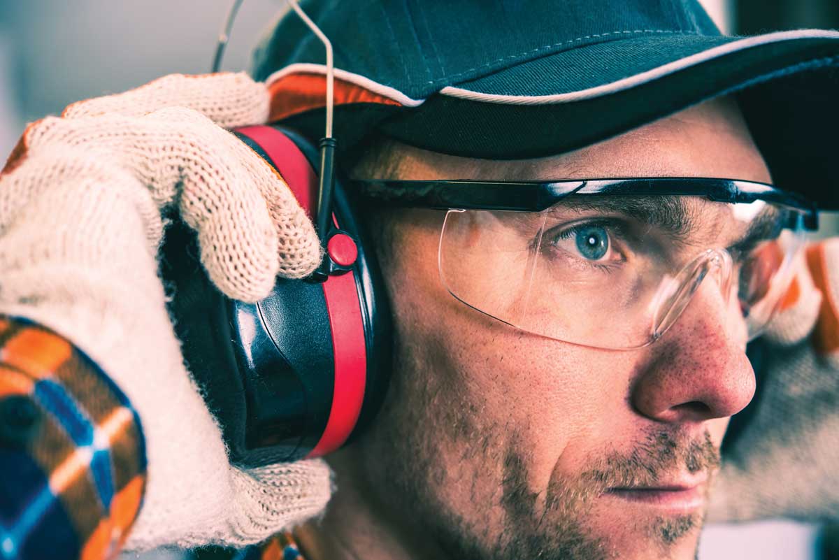 Man wearing protective hearing, gloves, and eyewear