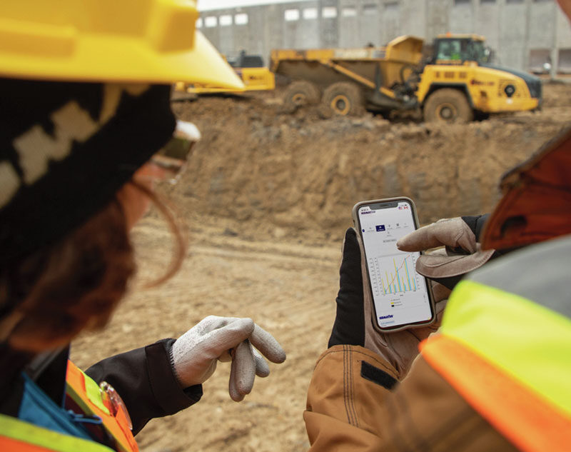 Two workers on construction site reviewing data on mobile device
