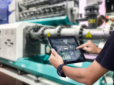 Hands holding tablet on blurred automation machine as background