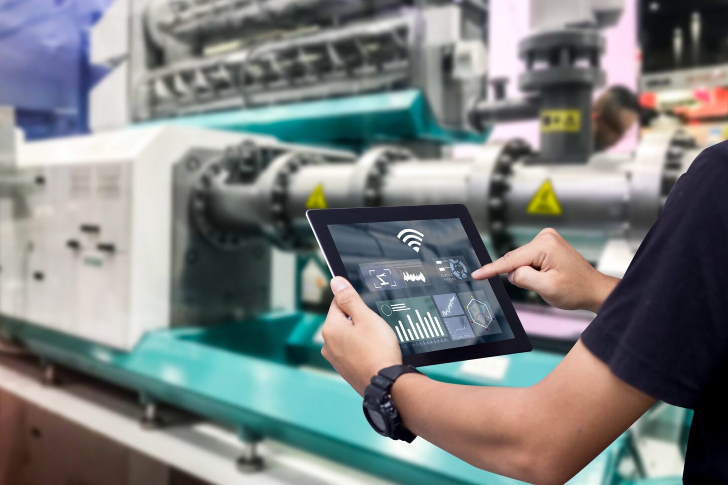 Hands holding tablet on blurred automation machine as background