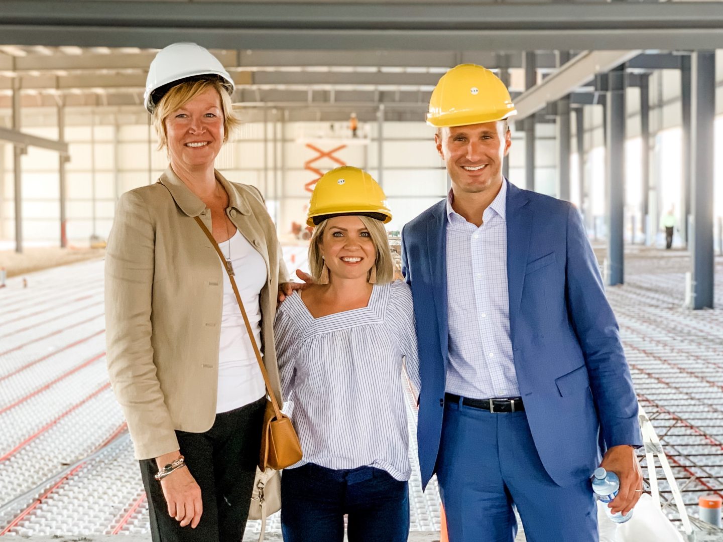Gail Eckert, Jessica Willis, and Matt Erhard posing for photo wearing hard hats on jobsite