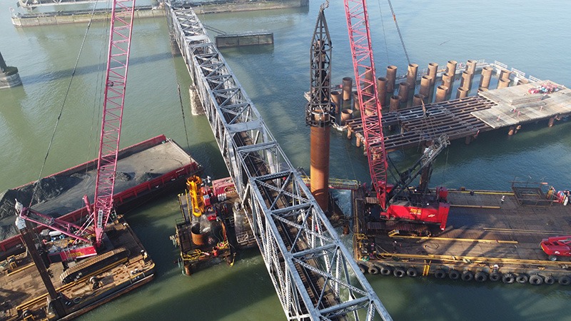 Large machinery on project site driving upstream pile and excavating sand using spherical grab