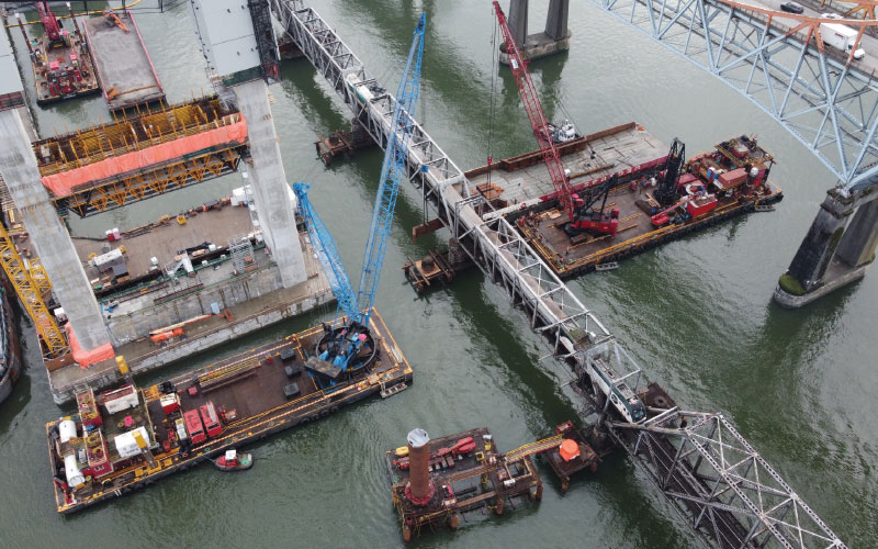 Installing one of two steel girders at Pier 7 with FRPD’s Peter D Anderson and Don Reid derricks. Protection Pier pile plicing underway in the background.