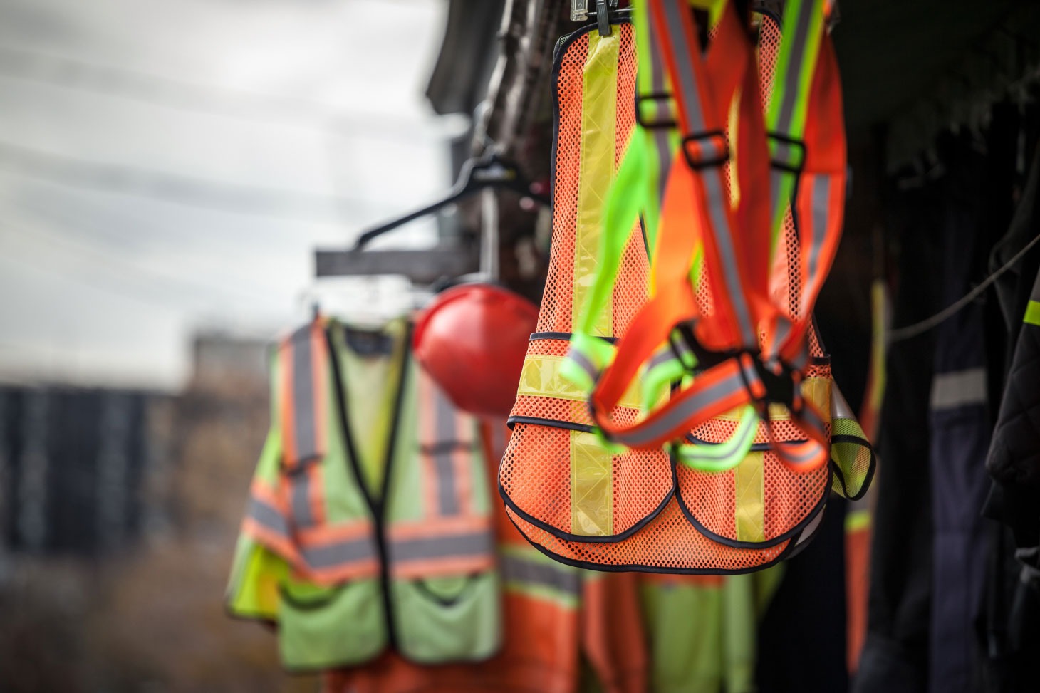 Safety vests and helmets hanging on hooks and hangers