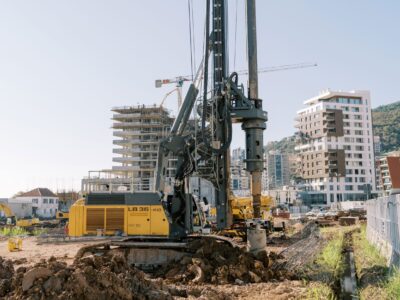 Drill rig with buildings and mountains in background.