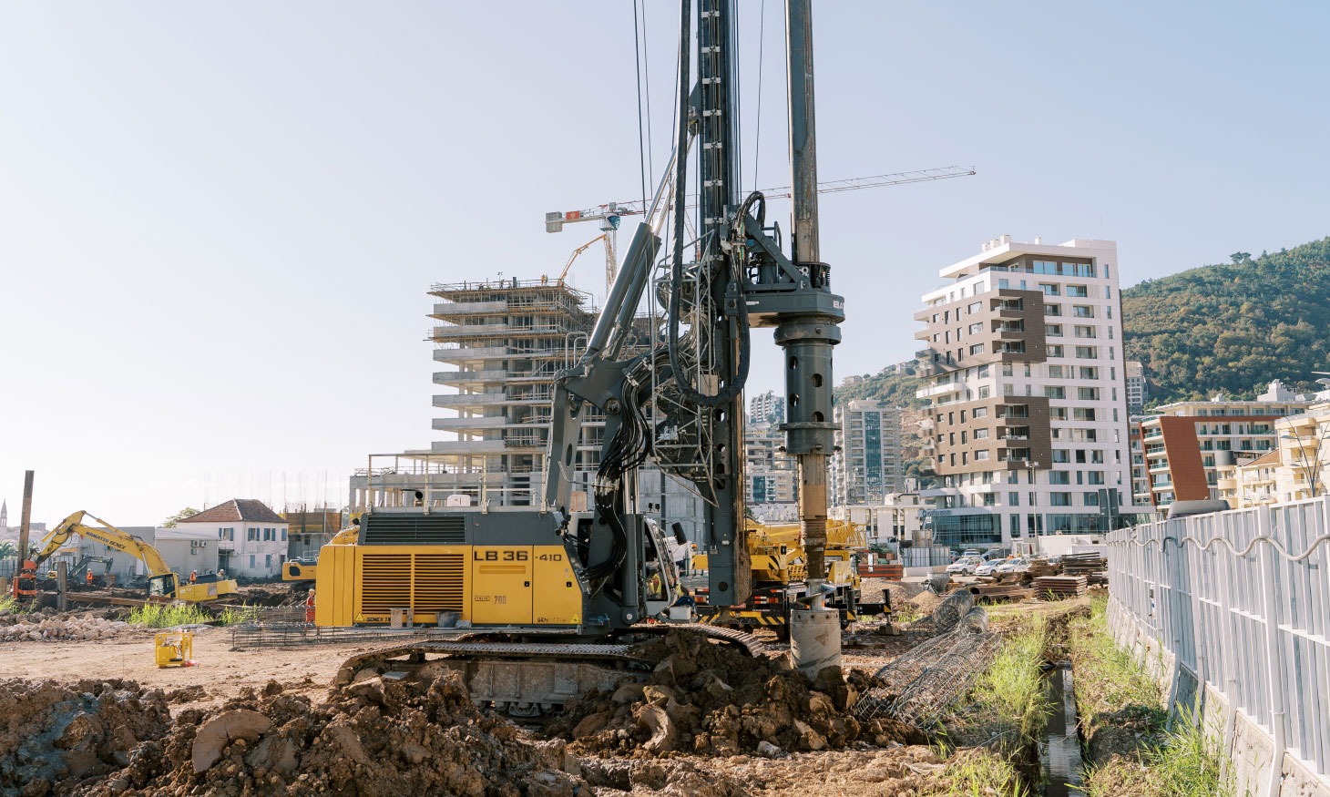 Drill rig with buildings and mountains in background.