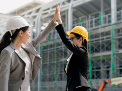 Two women in construction helmets high-fiving