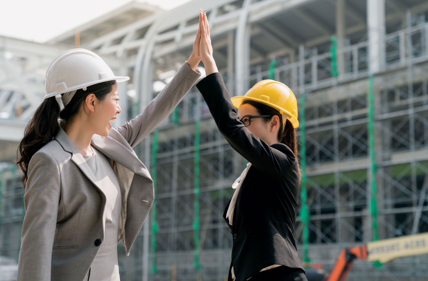 Two women in construction helmets high-fiving