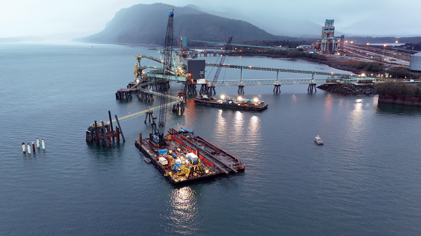 Heavy equipment on barge at dusk in heavy fog
