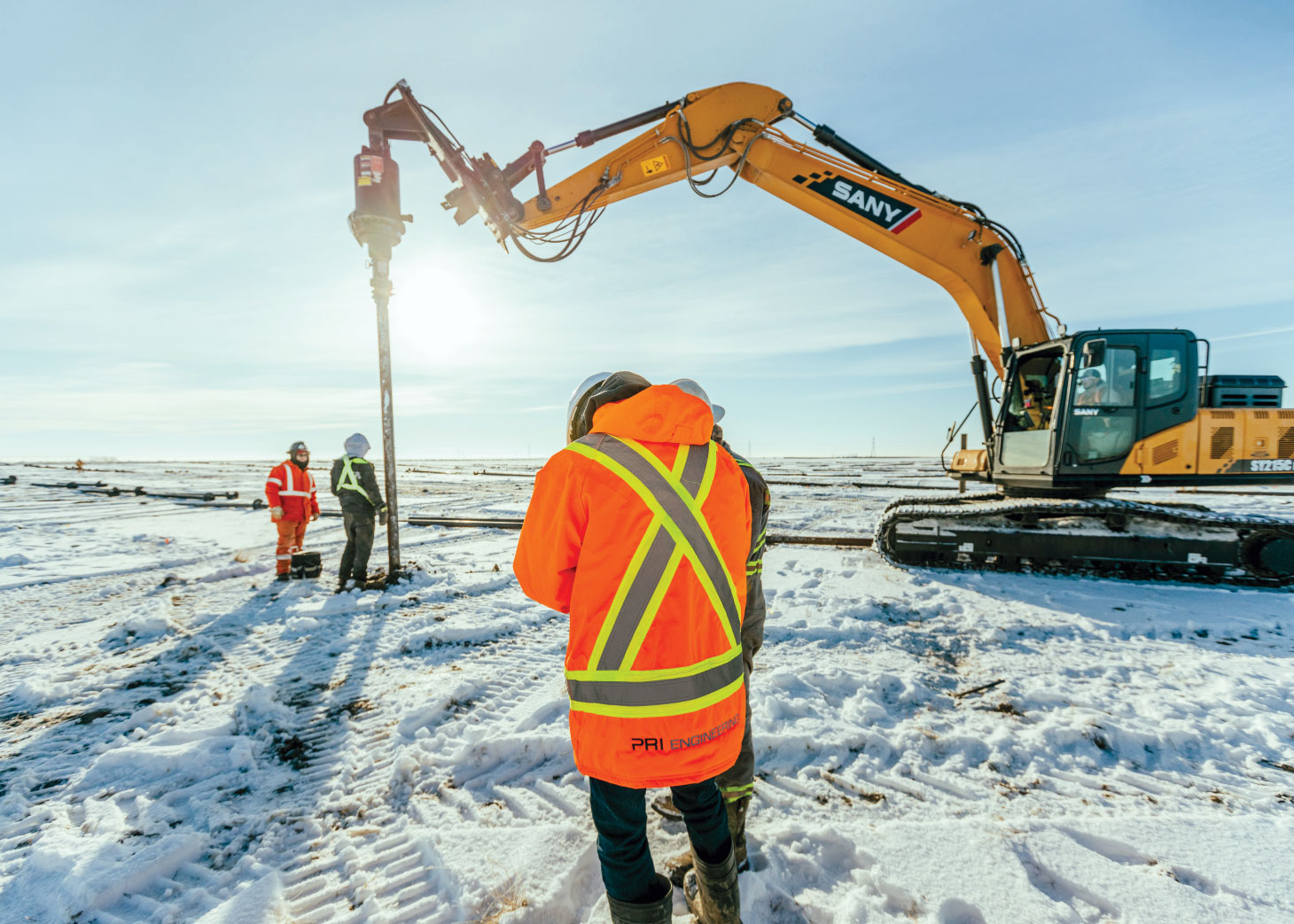Worker on site, drilling in snow-covered ground