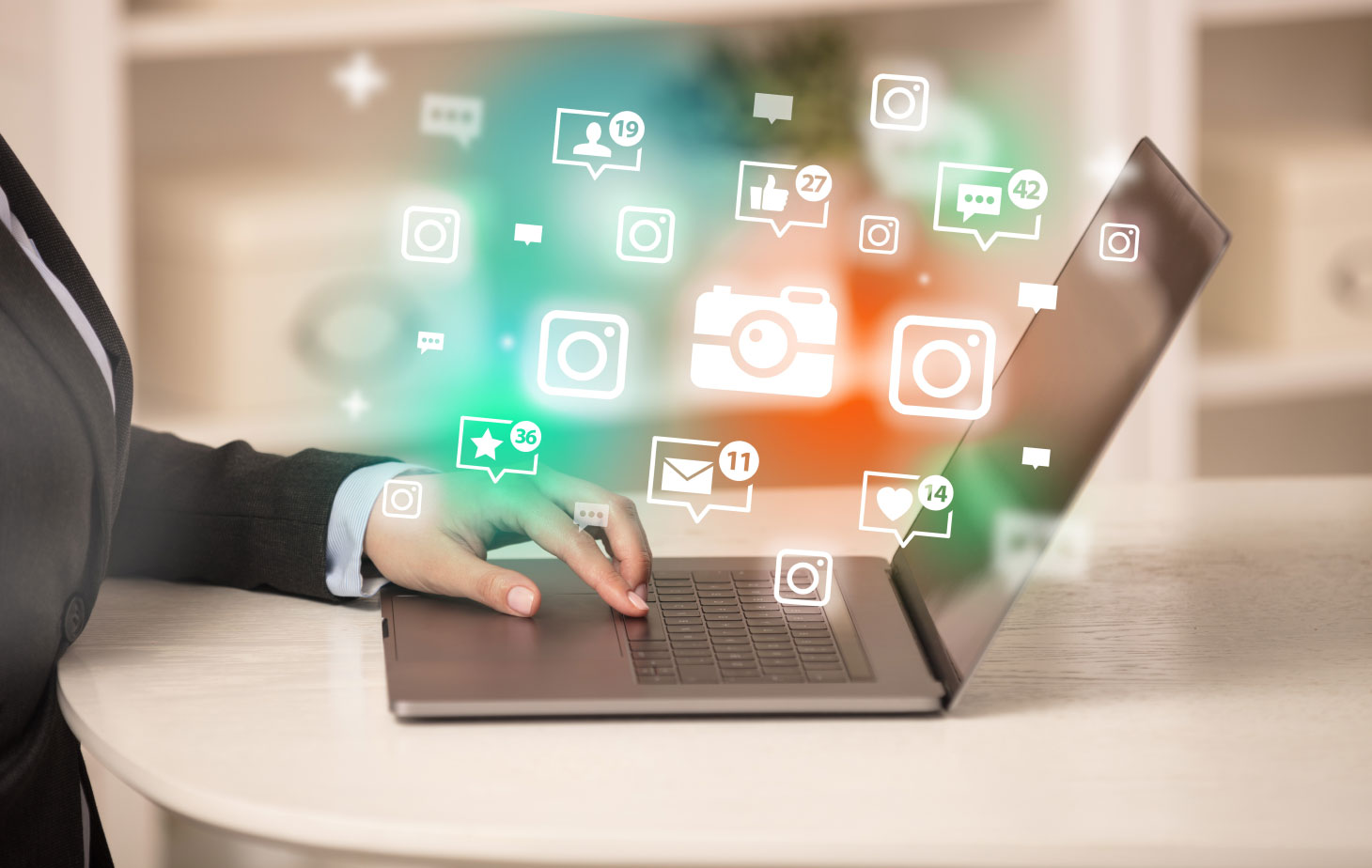 Graphic composition of hand typing on laptop with colourful icons hovering in the air above it