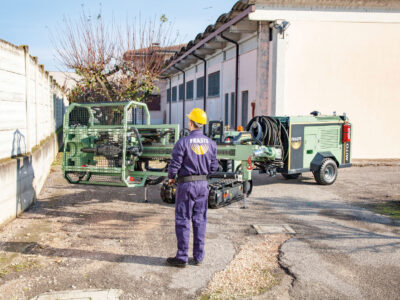 Employee in purple Fraste jumsuit and yellow helmet supervising work
