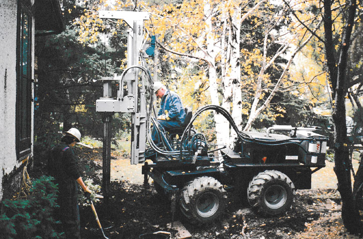Two workers repairing house foundation