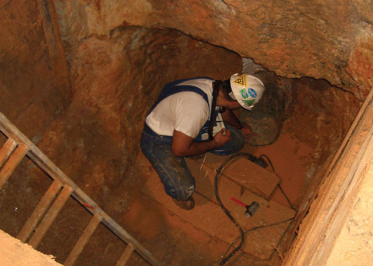 Worker in shaft, testing piles