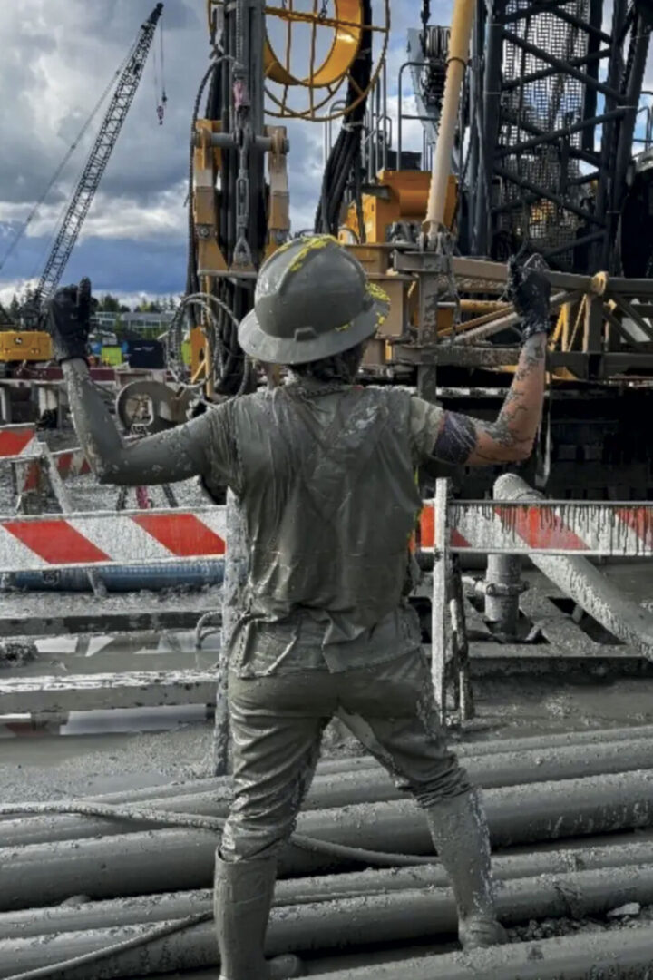 Jessica flexing, with back towards camera, covered in muck
