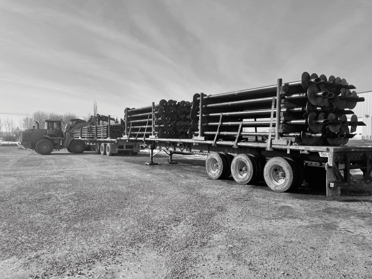 Helical piles loaded on truck trailers