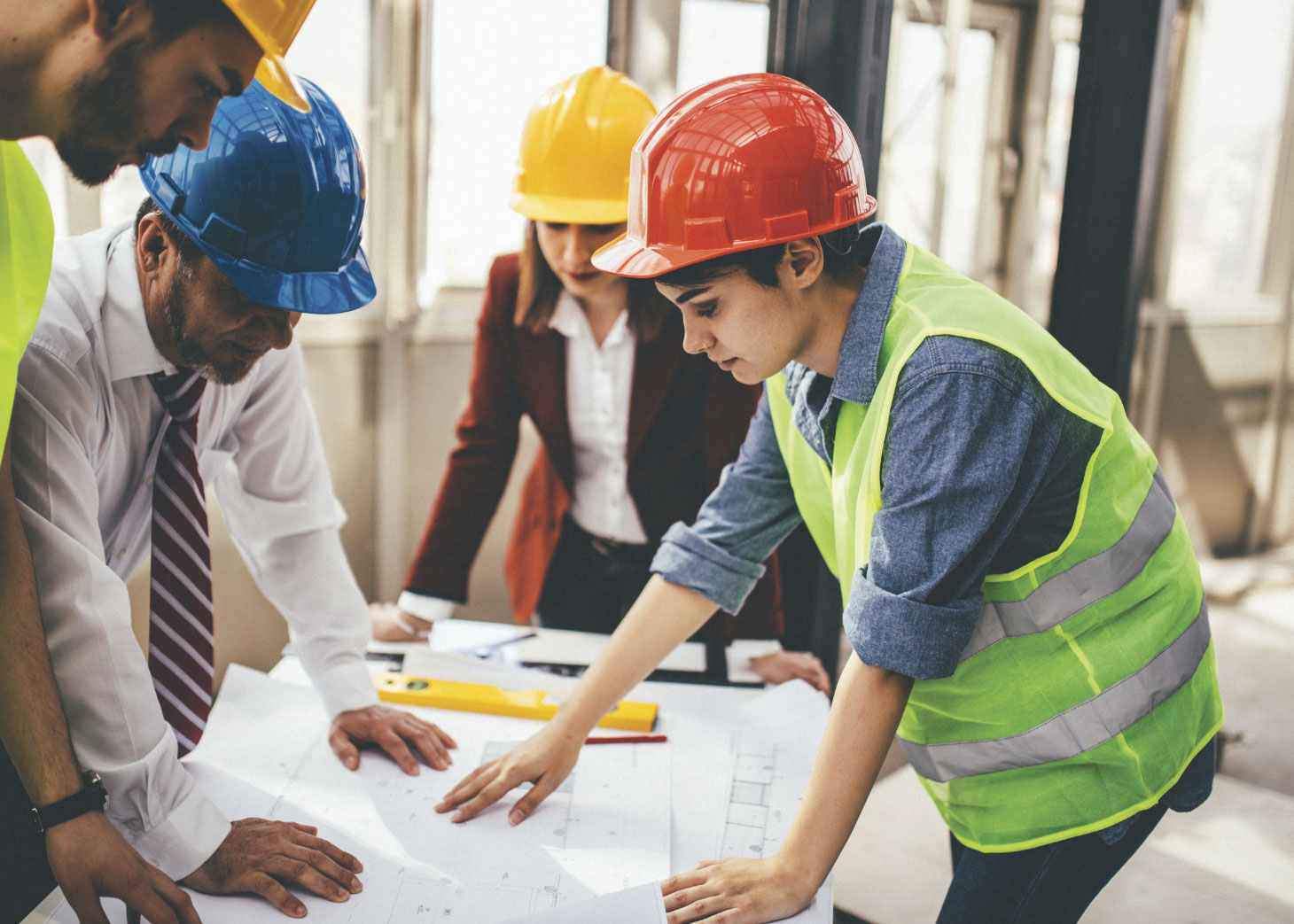 Group of construction workers gathered around table looking at blueprints
