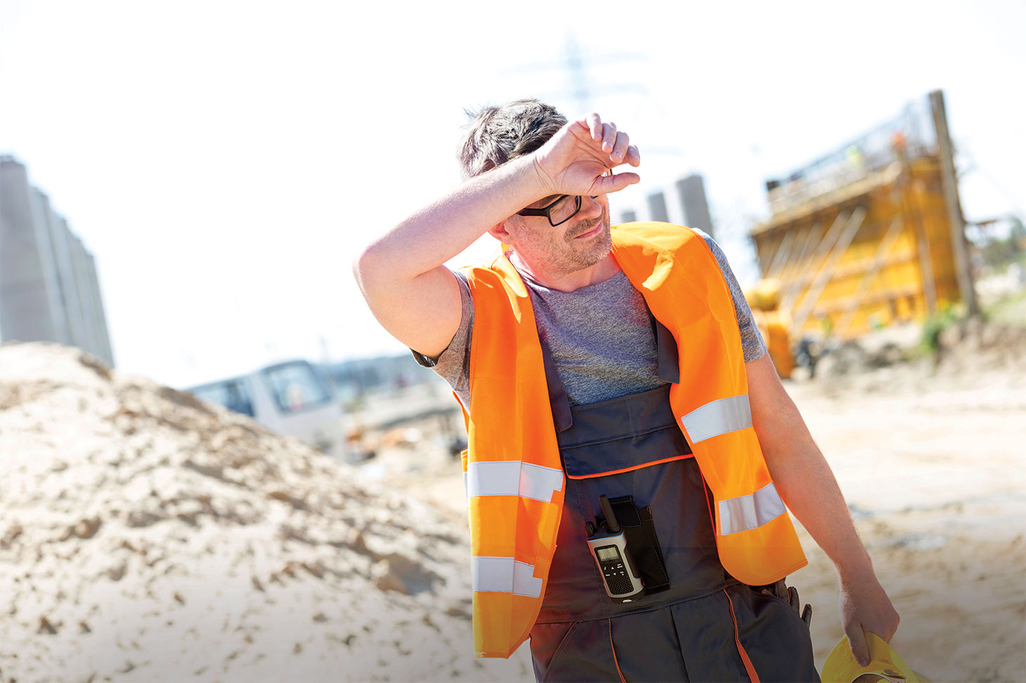 Tired construction worker wiping forehead at site