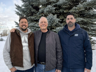 Barry, Jim and Tom pose for group photo in front of pine tree in winter