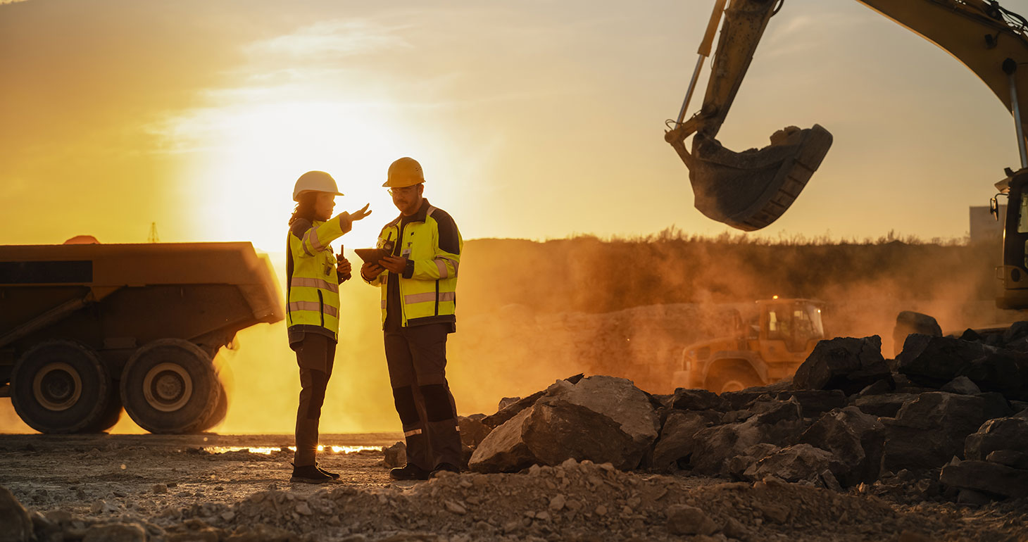 Workers on job site having dicussion, with sun setting in background